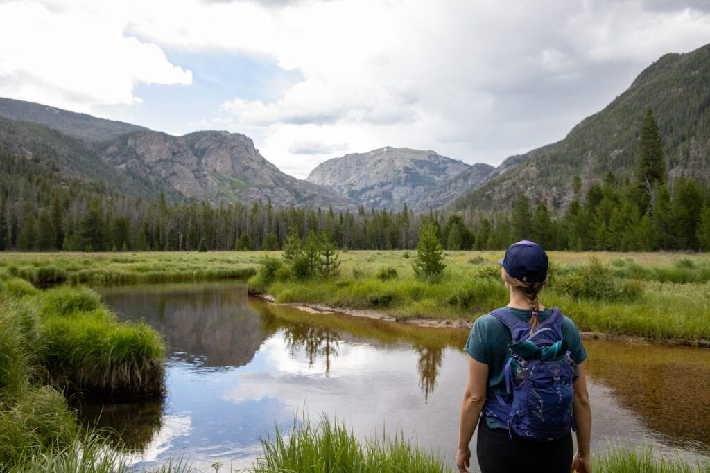 Woman stands next to a lake in Rocky Mountain National Park