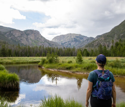 Woman stands next to a lake in Rocky Mountain National Park