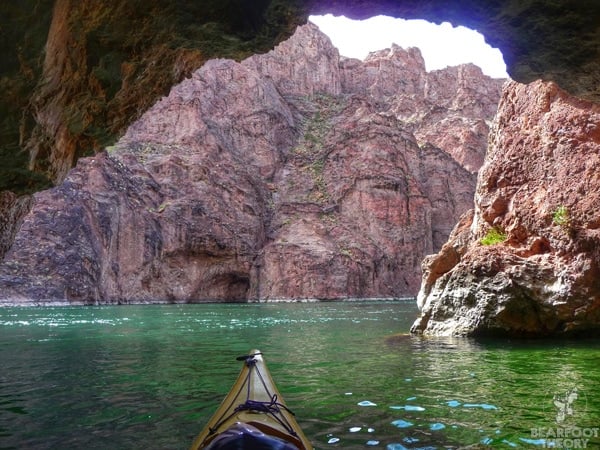 Kayaker under overhanging rock cave surrounded by red cliffs on the Black Canyon Trail in Nevada