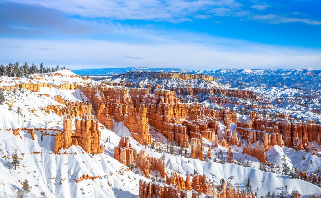 Red hoodoo rock formations in Bryce Canyon National Park poking through blanket of snow