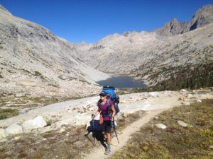 A woman smiles hiking on the John Muir Trail