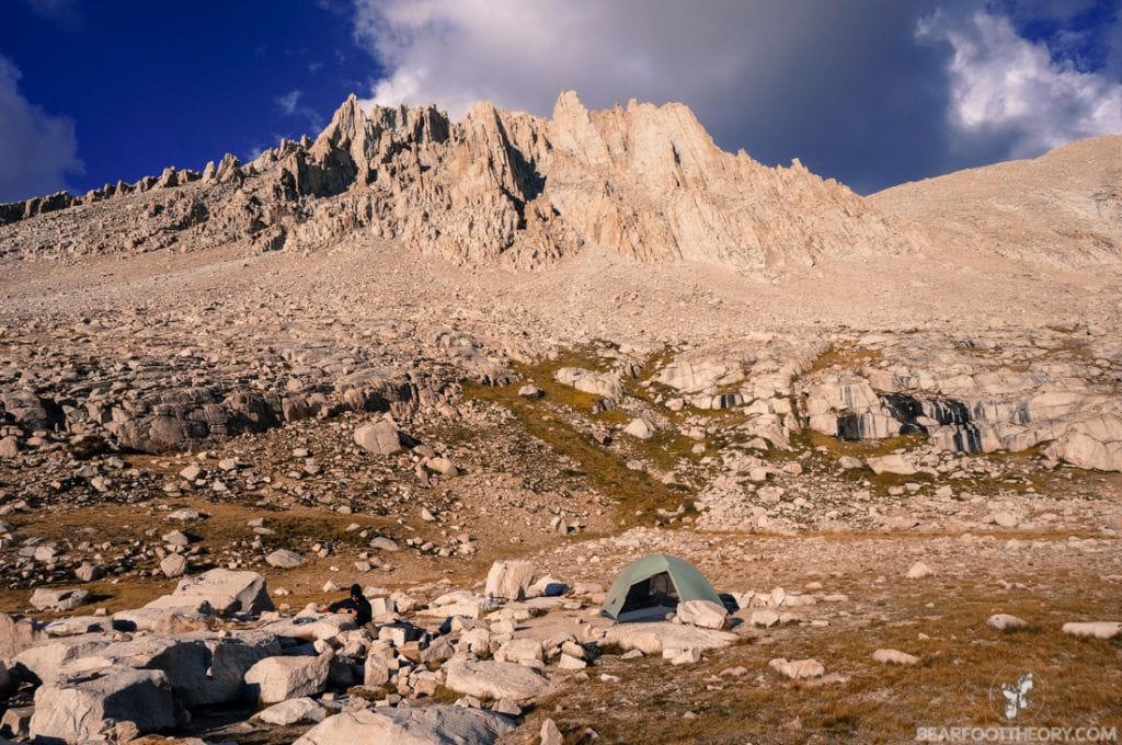 A backpacking tent set up against the backdrop of jagged granite peaks on the JMT