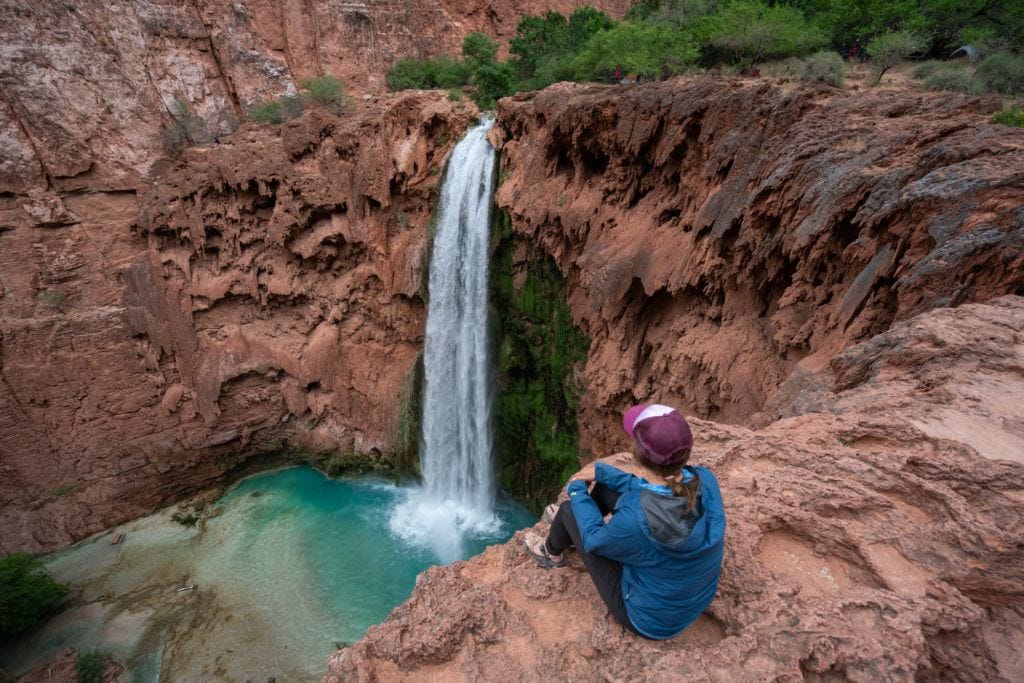 Kristen Bor sitting on the edge of Mooney Falls next to the camping at Havasu Falls