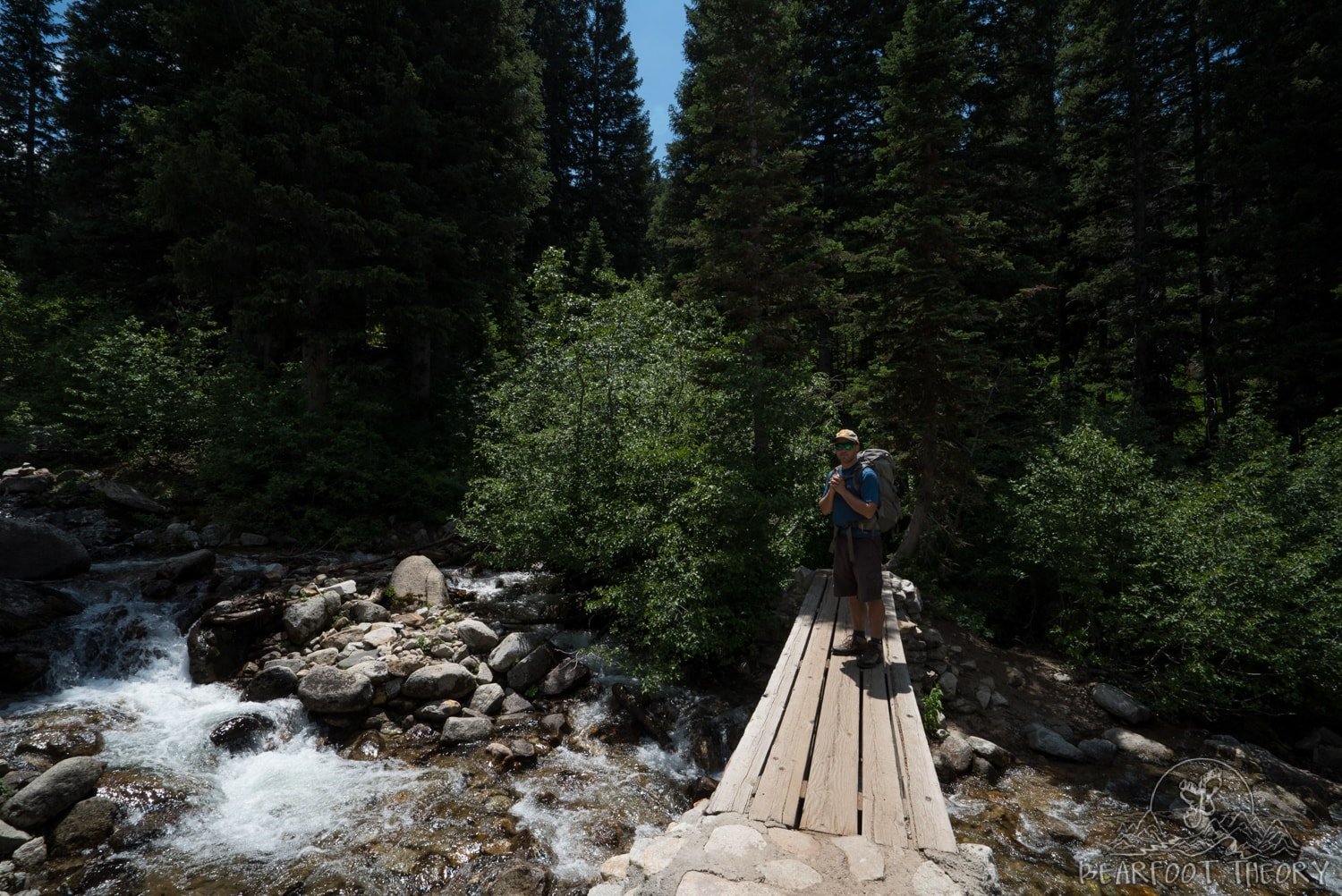 Man on wooden bridge over river on Red Pine Lakes trail in Utah