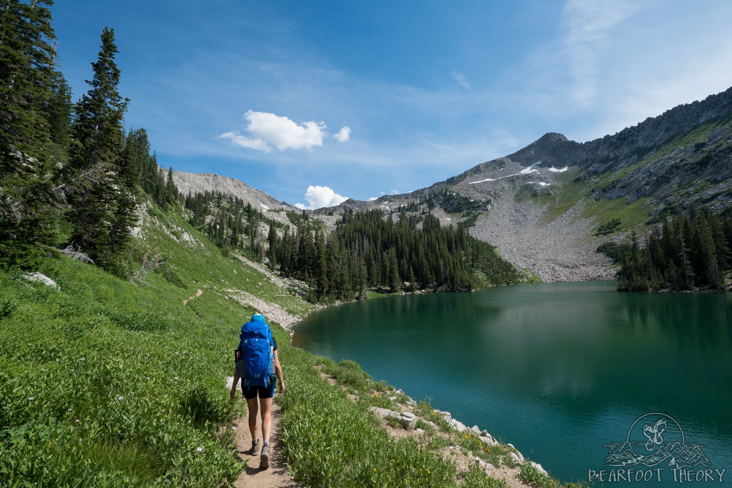 Woman backpacking on trail next to alpine lake outside of Salt Lake City