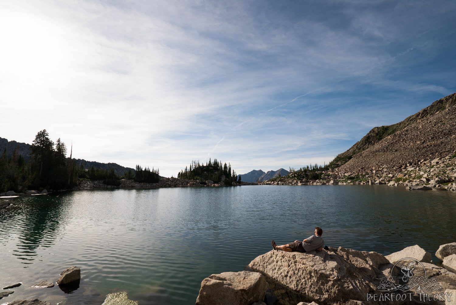 Man laying on rock next to Red Pine Lake outside of Salt Lake City, Utah