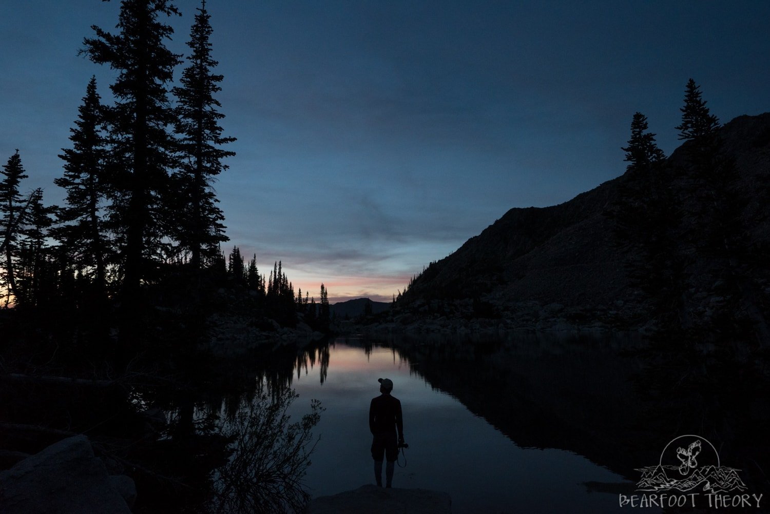 Silhouette of man standing next to Red Pine Lake at sunset