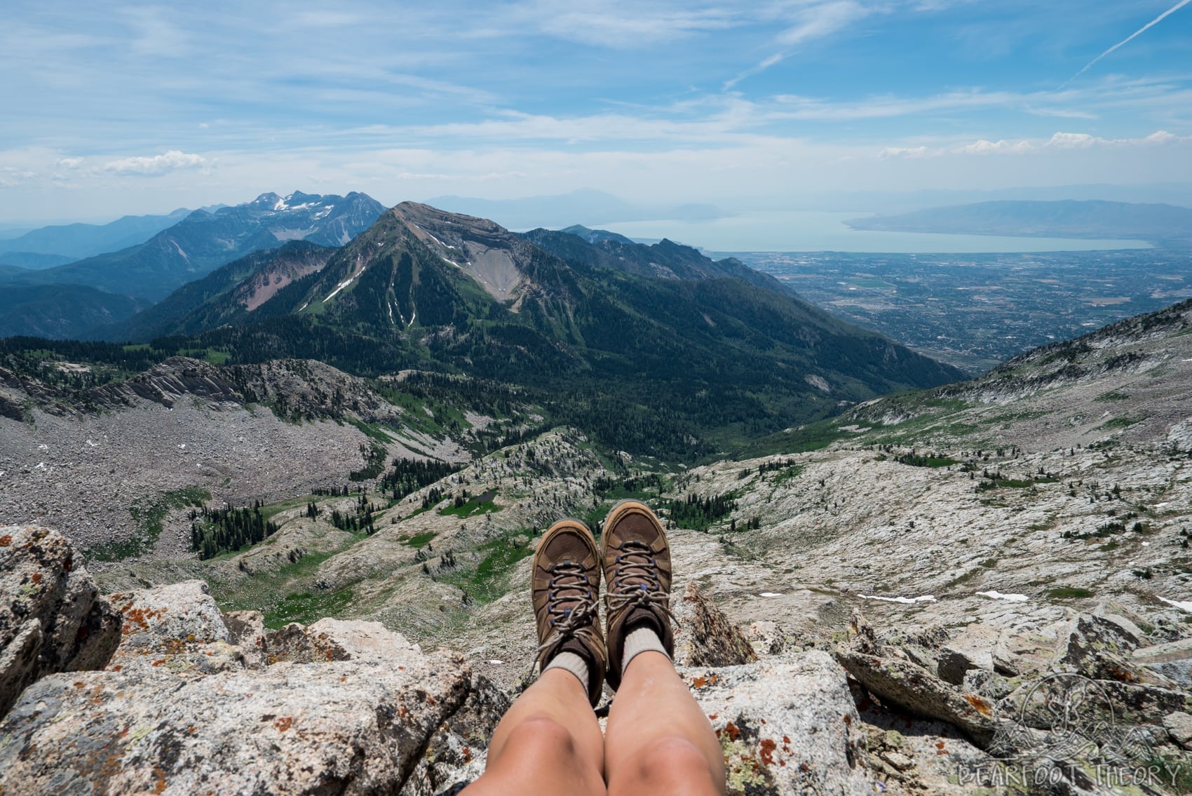 Photo out over hiker's feet from the summit of the Pfeifferhorn, the third tallest peak near Salt Lake City in the Wasatch Mountain Range