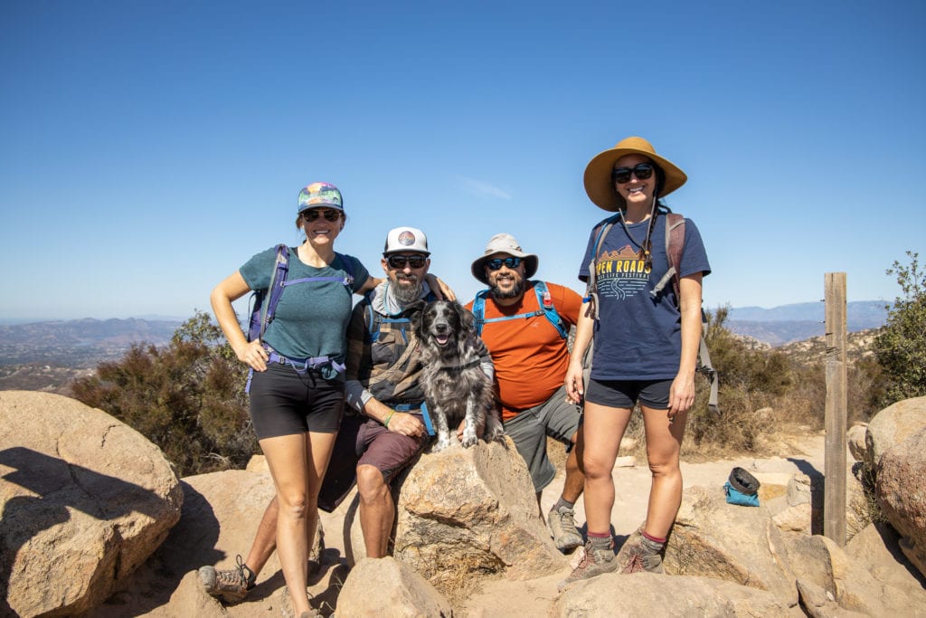 Friends hiking with a dog at the top of a summit