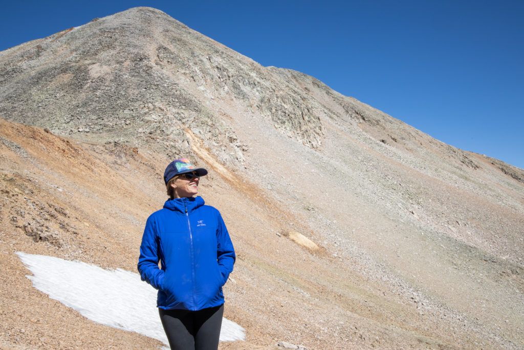 Kristen standing in front of mountain peak wearing Arc'teryx jacket