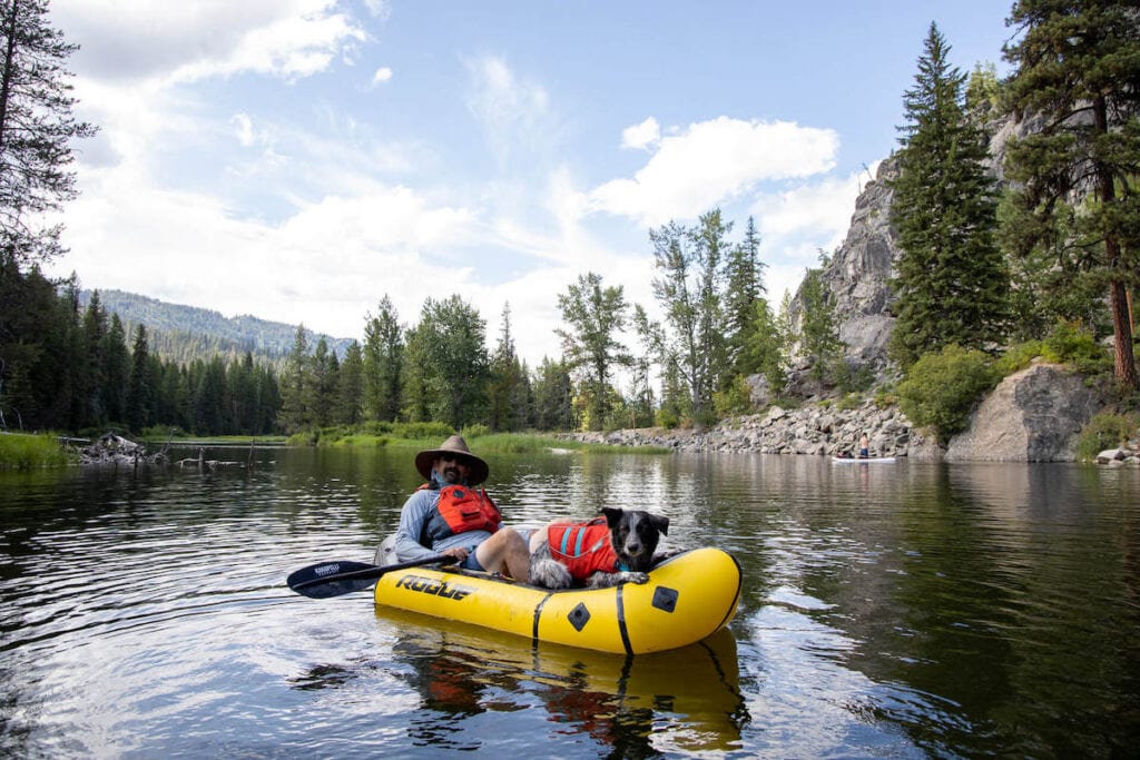 Man sitting in packraft with down on Payette River outside of McCall Idaho