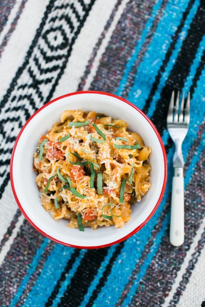 one pot camping meal pasta in a bowl with a striped blanket underneath