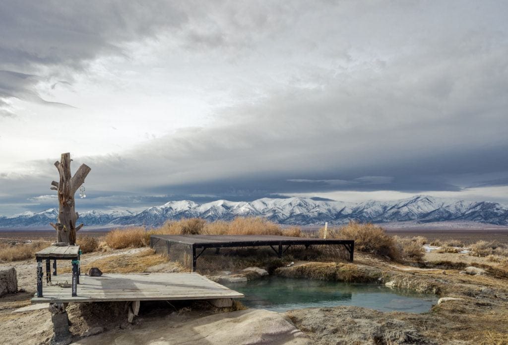 A natural hot spring in Nevada - Spencer Hot Springs - with snowy dusted mountains in the background