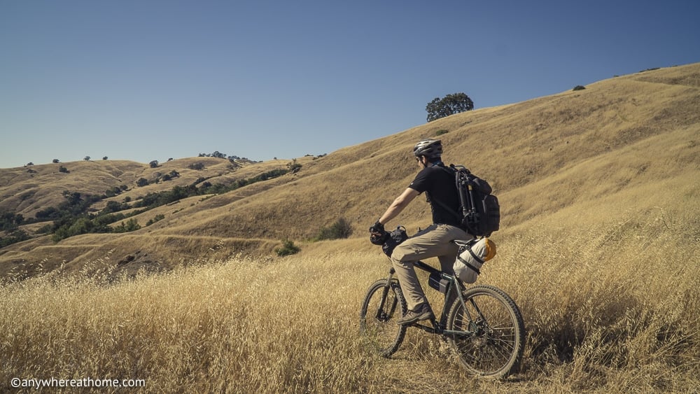 Man mountain hiking through grassy hills in Henry Coe State Park