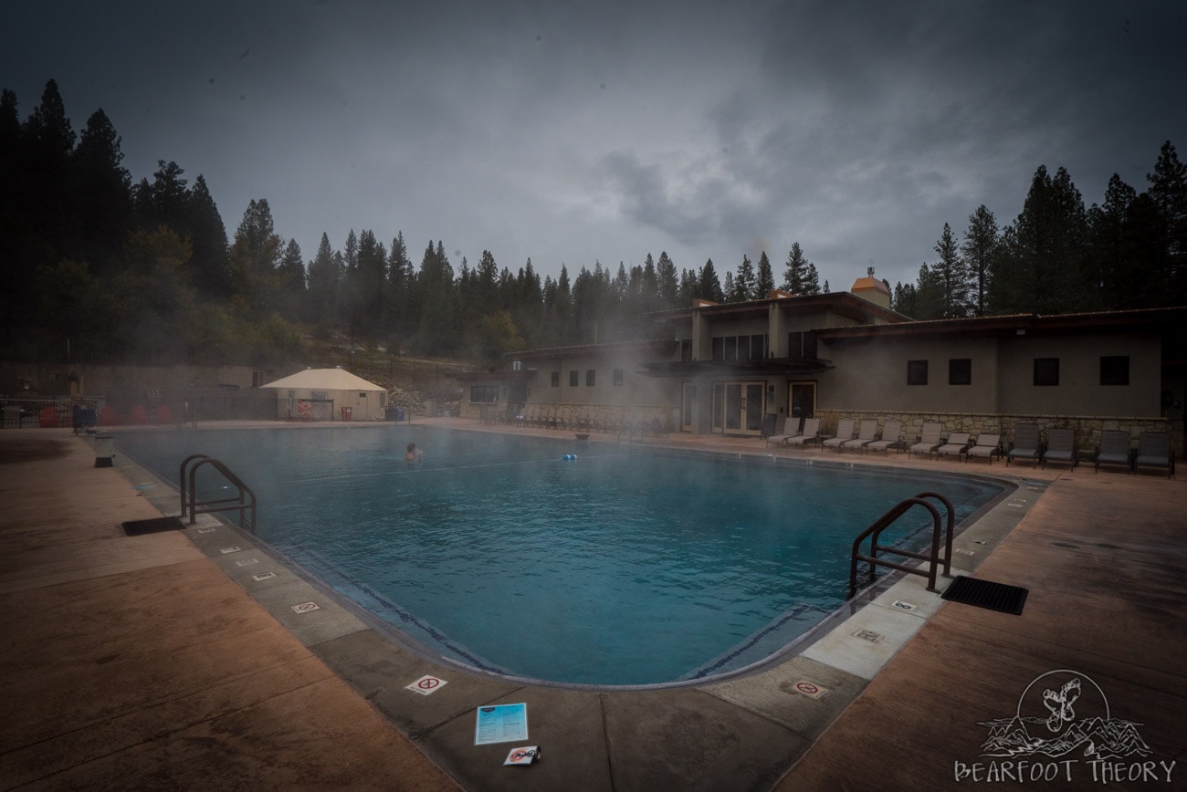 Large hot springs pool with steaming rising up at The Springs in Idaho City Resort surrounded by pine forest