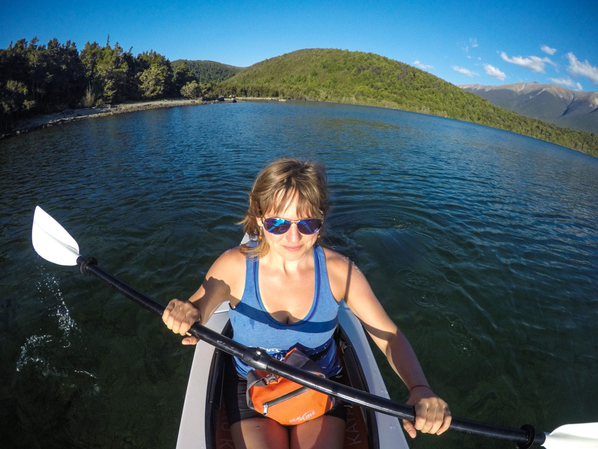 A woman holds a kayak paddle while looking ahead at the water.