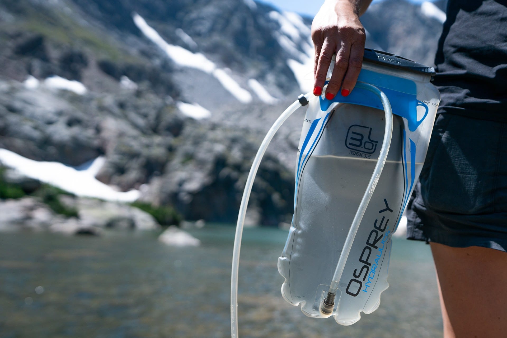 A person holds a Osprey hydration bladder by their side