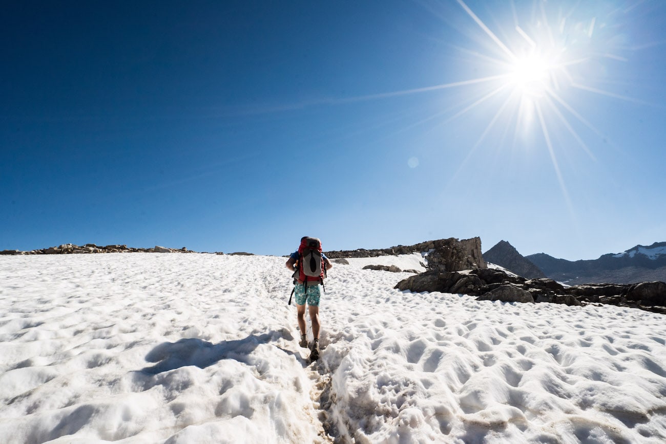 Hiker traversing through large patch of snow in the Eastern Sierra of California