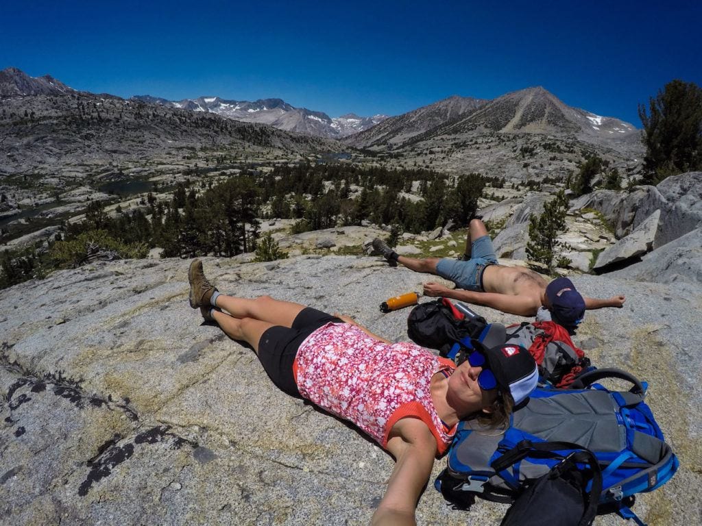 Two hikers laying on large rock in backcountry area of Dusy Basin in Eastern Sierra of California