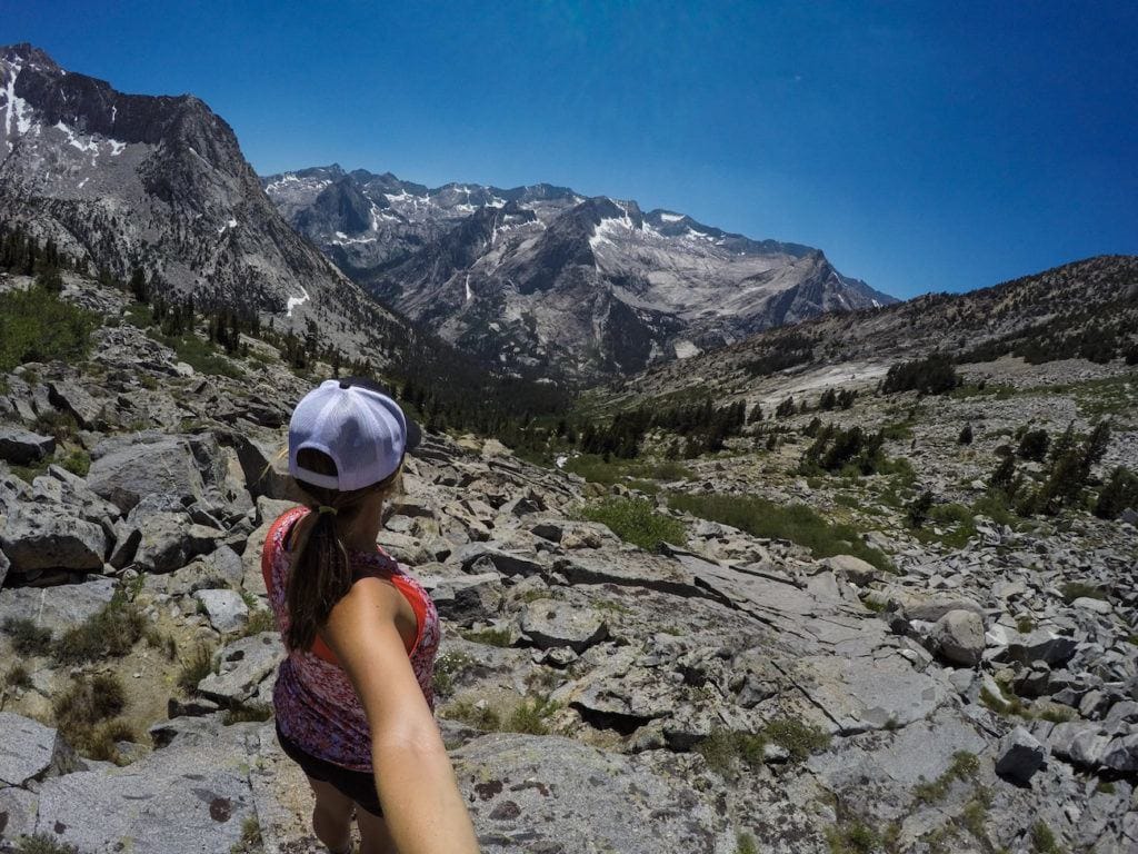 Woman taking selfie from behind while looking out over scenic high alpine landscape in Eastern Sierra of California