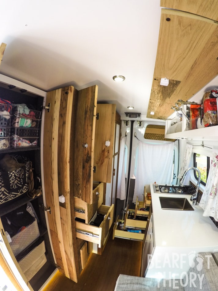 Interior view toward the back of Kristen's first converted Sprinter camper van showing all the storage including floor to cieling cabinets, overhead cabinets, and drawers