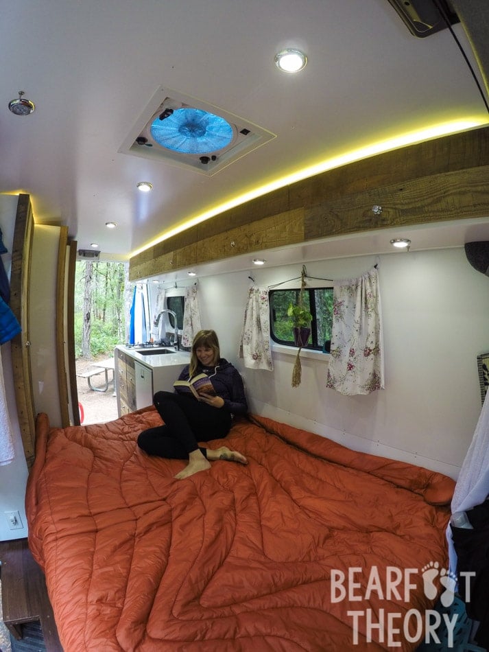 Interior photo of Kristen's first MErcedes Sprinter camper van showing the convertible sofa bed unfolded into a queen size bed