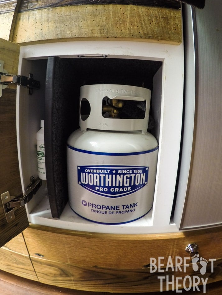 The 1 gallon propane tank is stored in a cabinet under the sink in Kristen's first Sprinter camper van which powers the dual propane burner in the galley