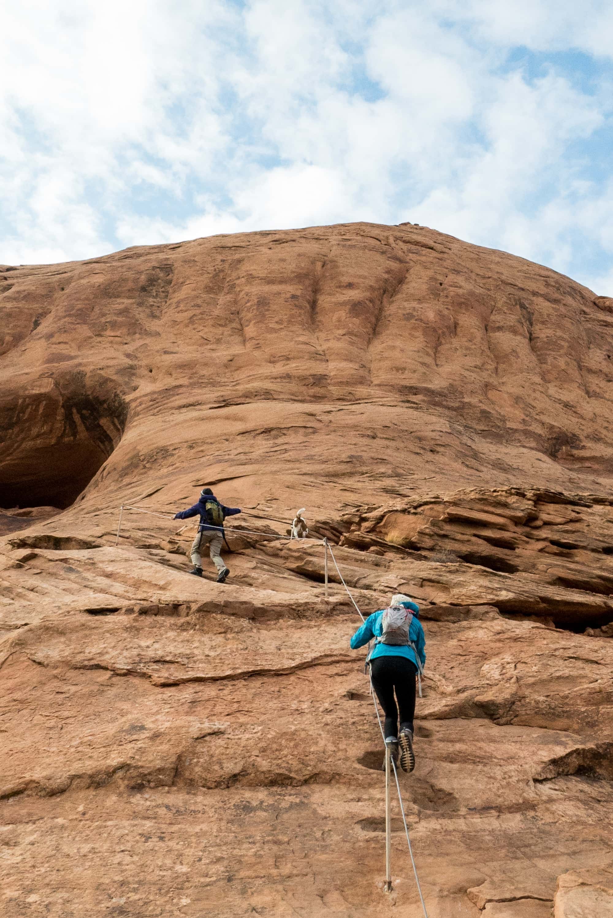 People walking up sandstone slab of rock in Moab using rocks to stay balanced