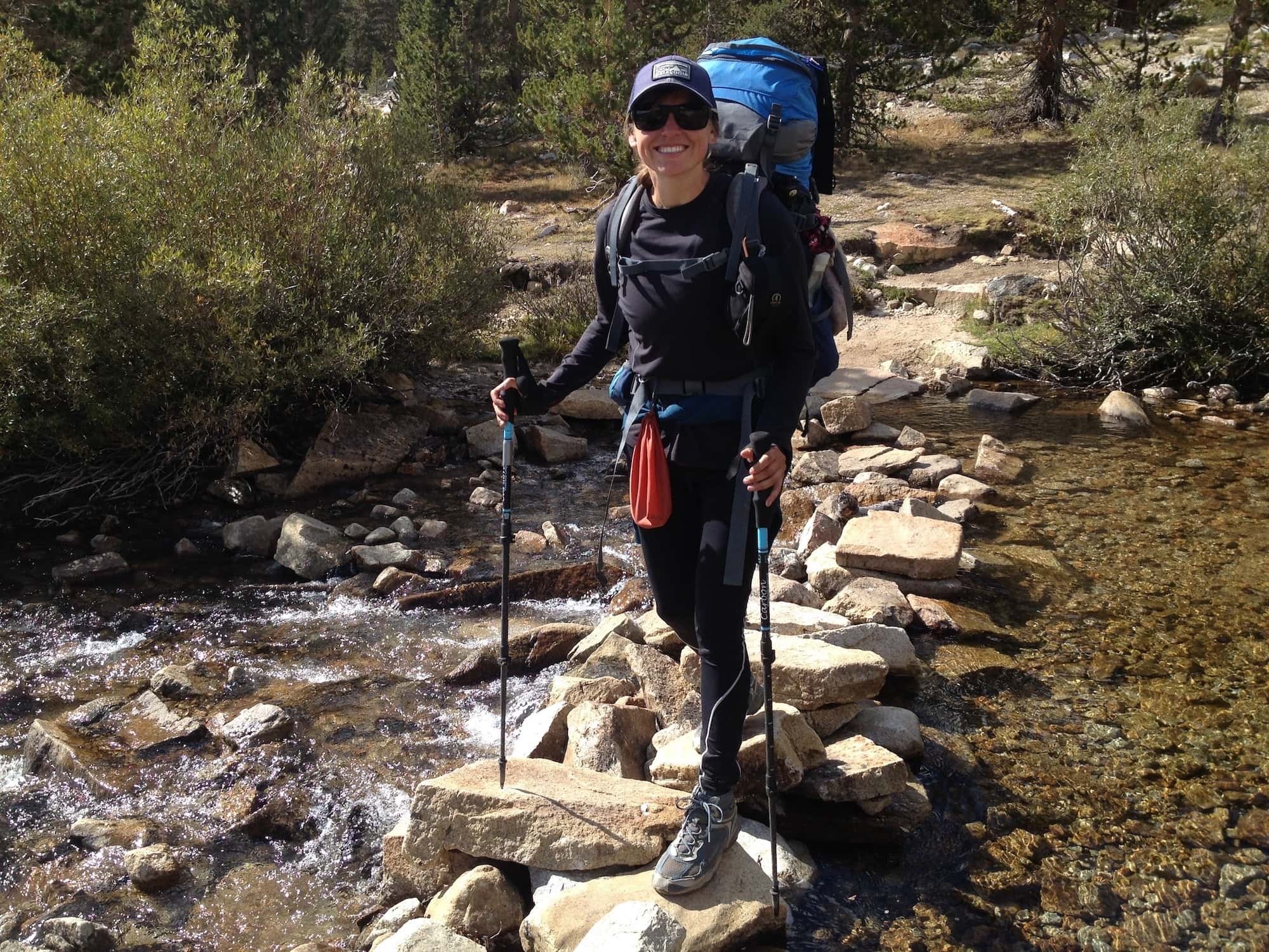 Kristen crossing a stream on a pile of rocks