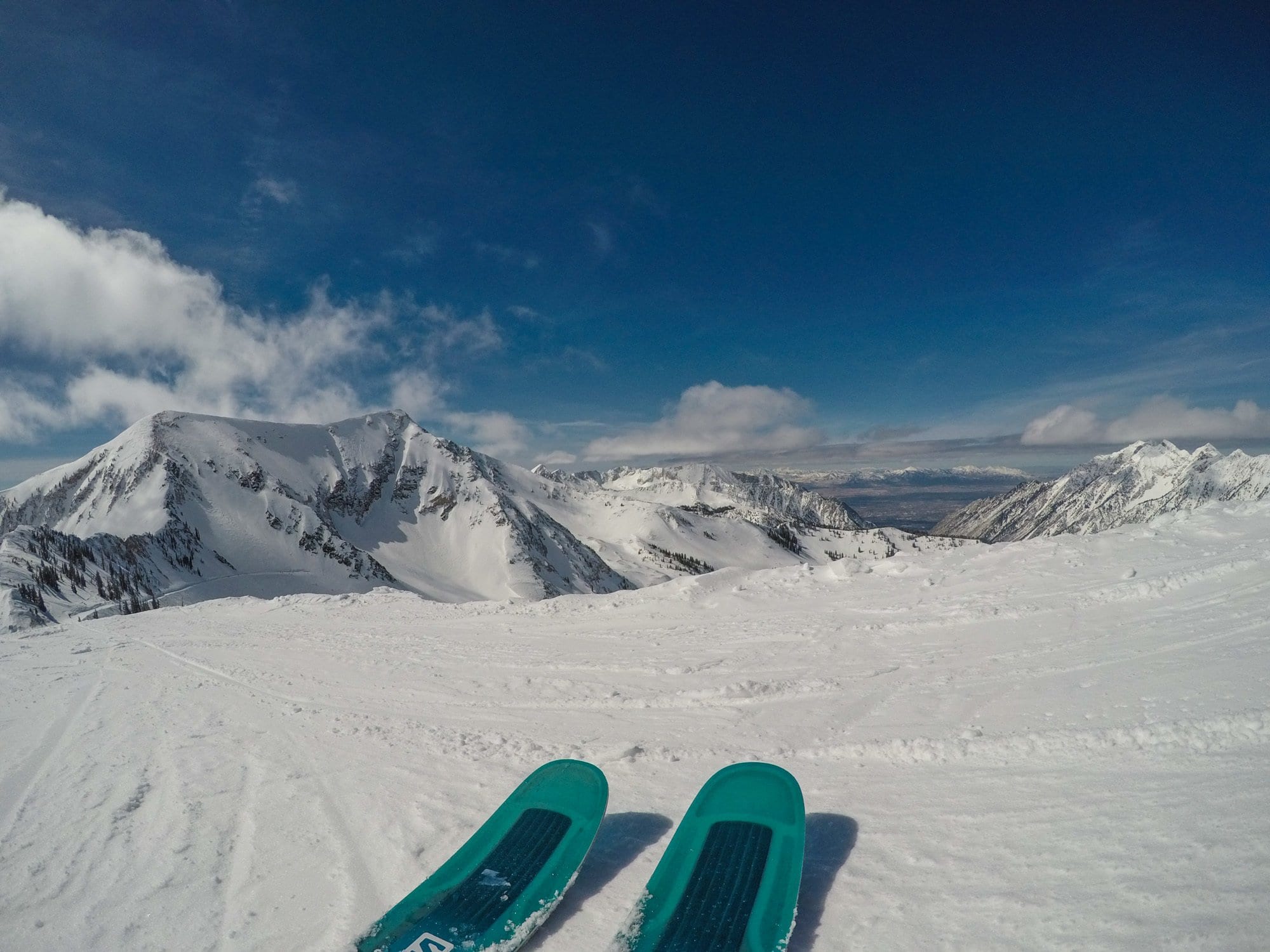 Photo out over tips of skis on snowy slope at Alta Resort with snow-covered peaks in distance