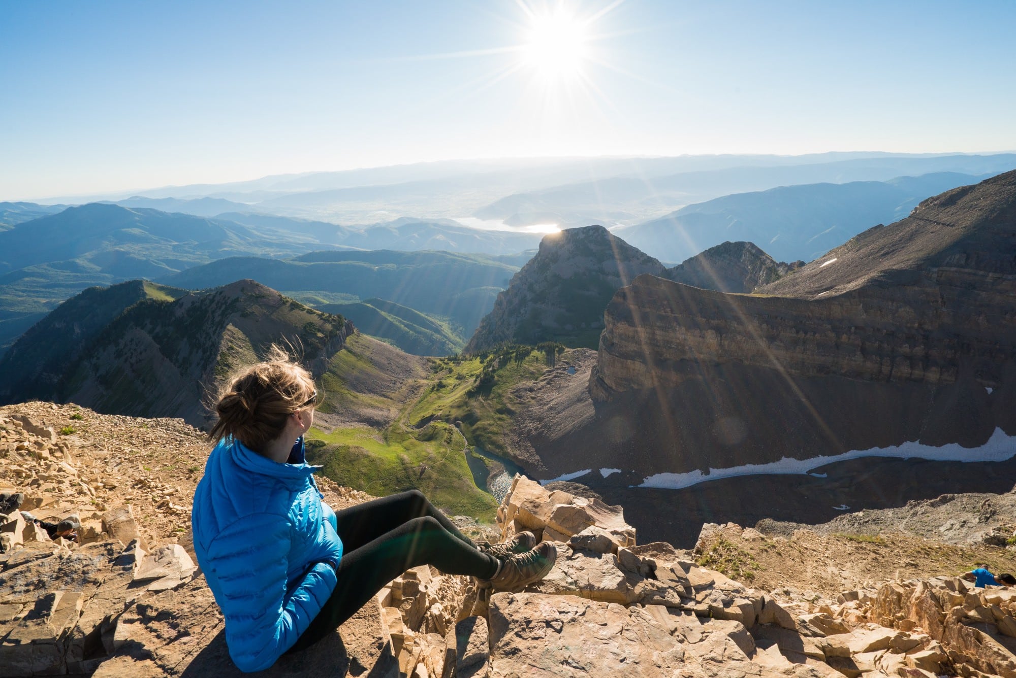 Woman sitting on summit of Mount Timpanogos in Utah shortly after sunrise