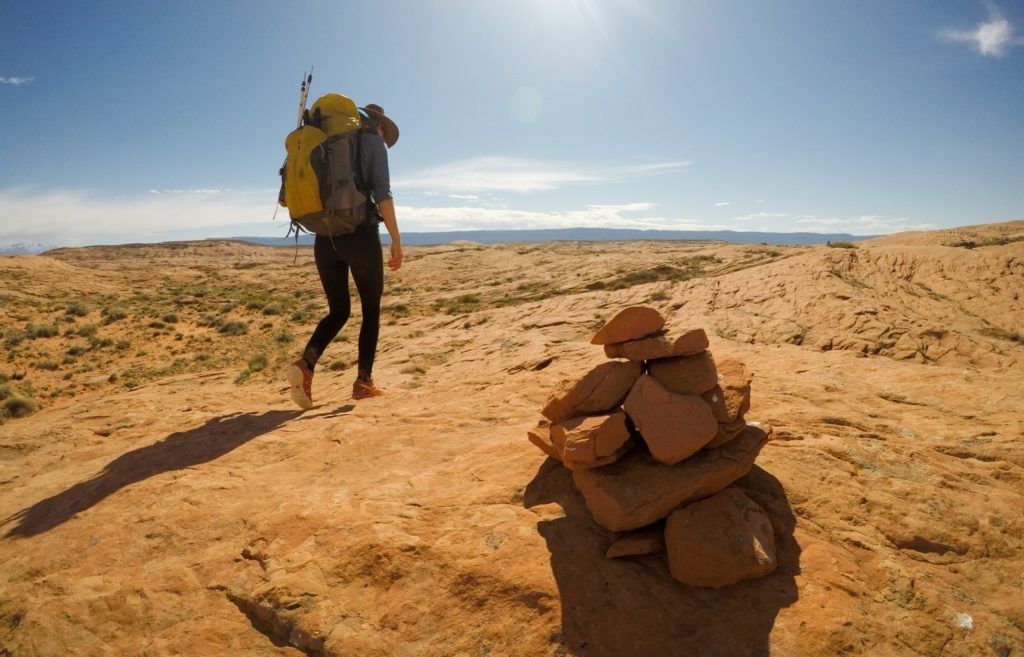 Woman hiking past a rock cairn