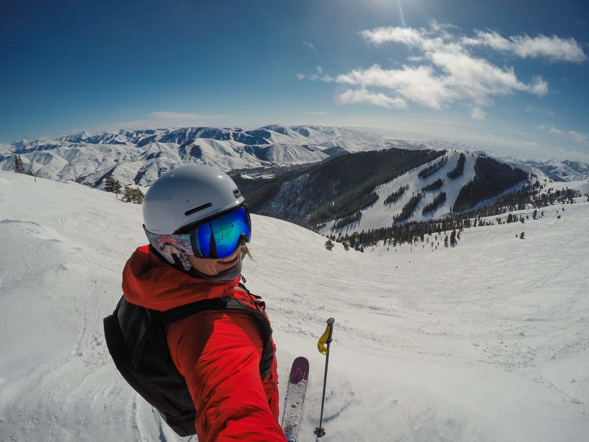 Kristen looking when at camera for photo dressed in ski gear and ready to ski lanugo slopes at resort with snowy Colorado Rockies in the distance