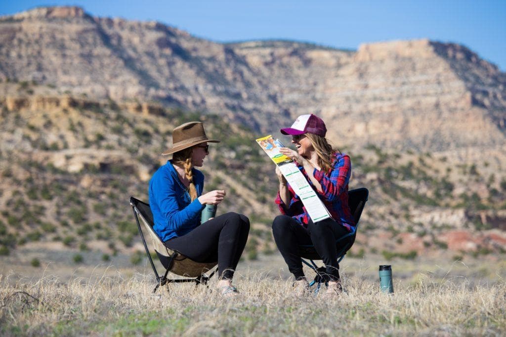 Two women sitting in camp chairs with a hiking map in Grand Staircase Escalante National Monument