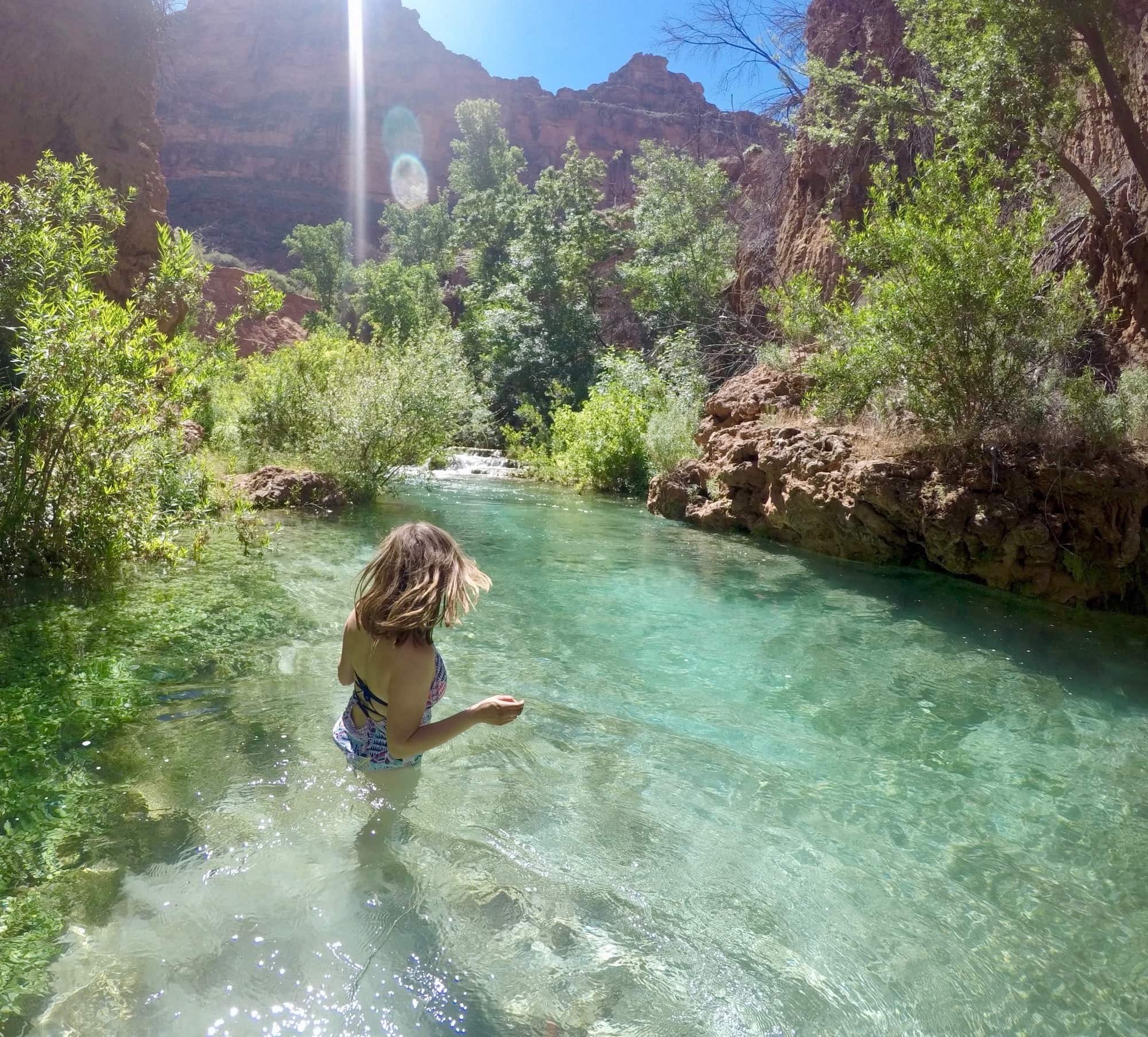 Woman taking a dip in crystal clear turquoise waters of Havasu Creek