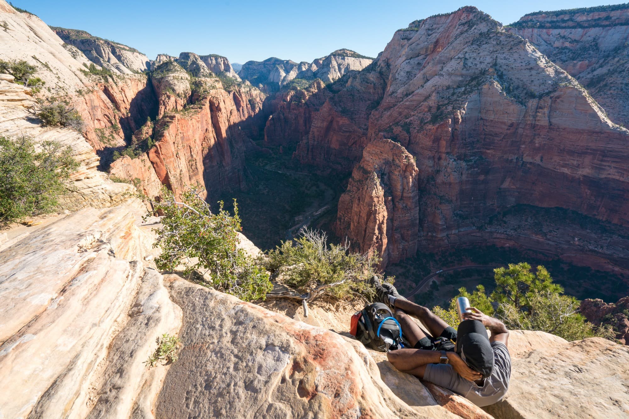 Man reclined on rock slabs looking out over spectacular views of Zion National Park from Angel's Landing