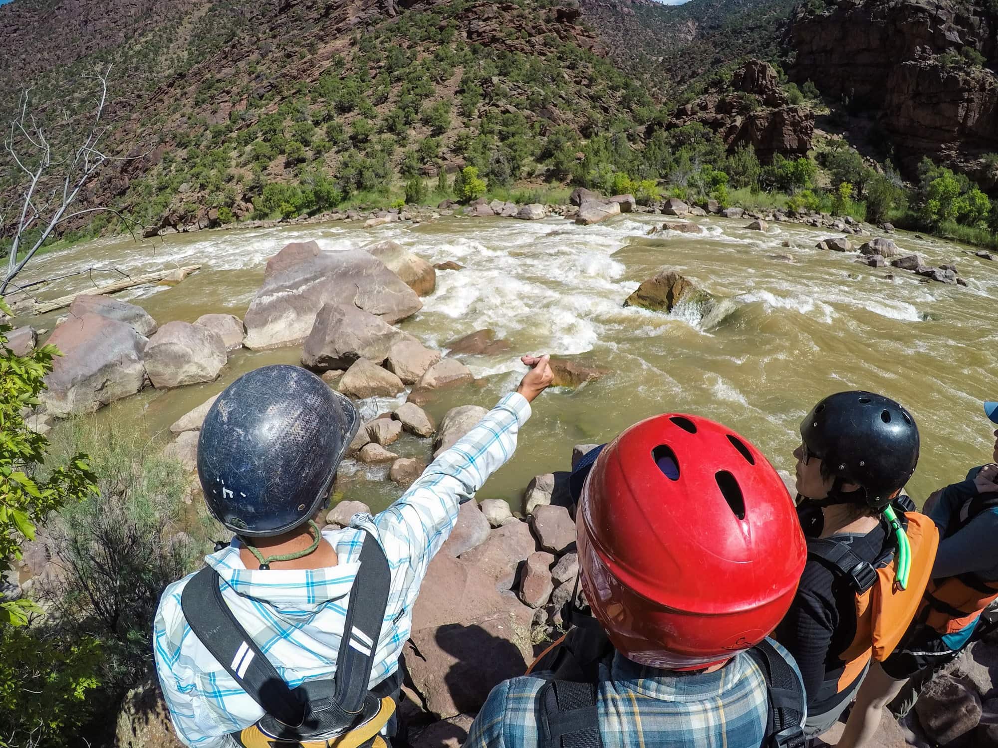 People wearing helmets watching rapids on the OARS Gates of Lodore trip