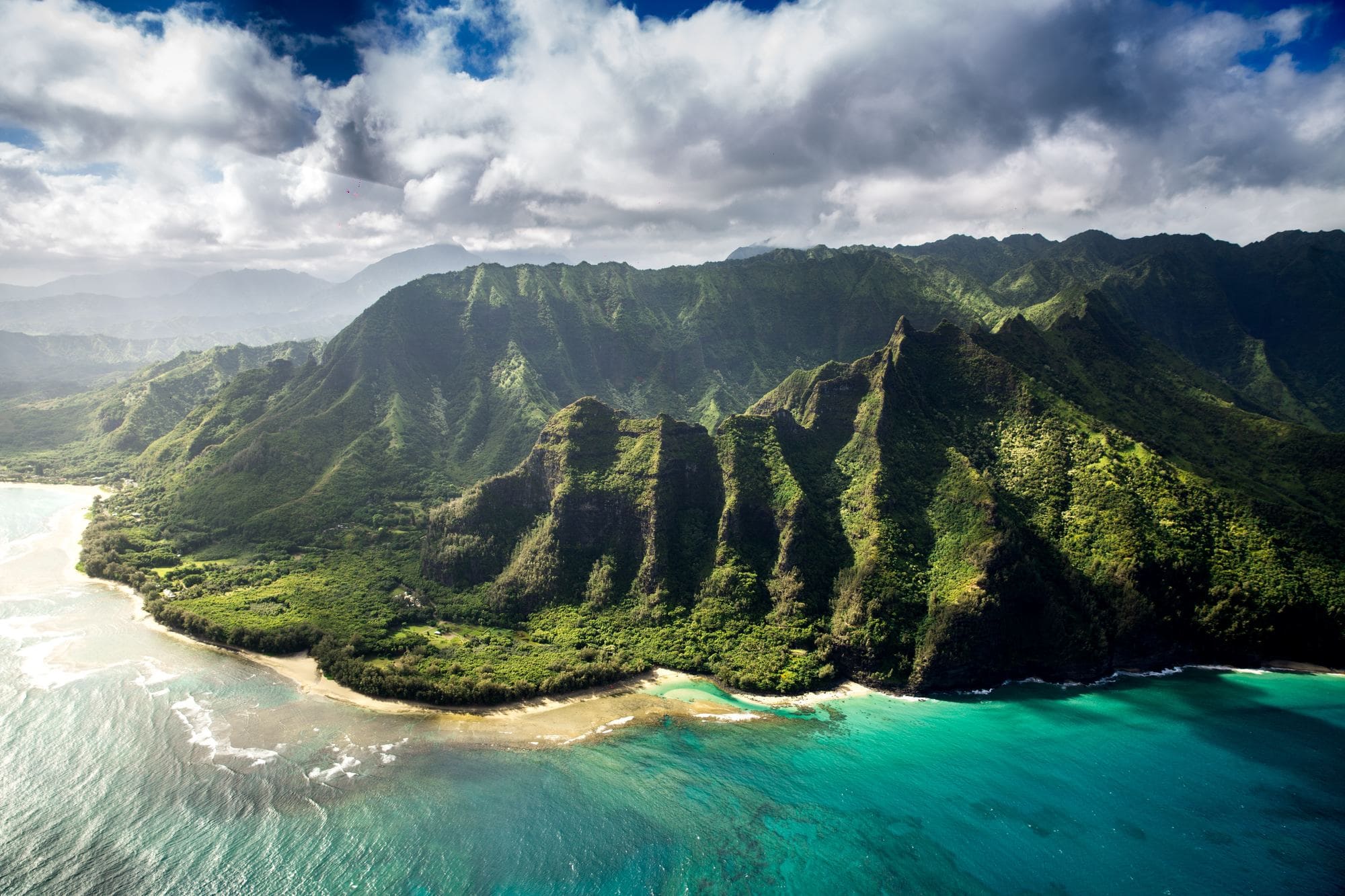 Aerial views of green cliffs on Kauai meeting the ocean