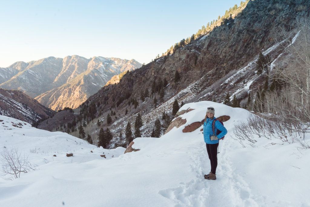 Kristen looking back at camera on snowy hike with mountains in background