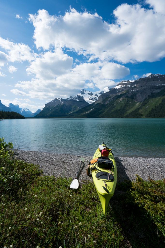 Kayak on shores of Maligne Lake in Alberta with tall Rocky Mountains rising up from water