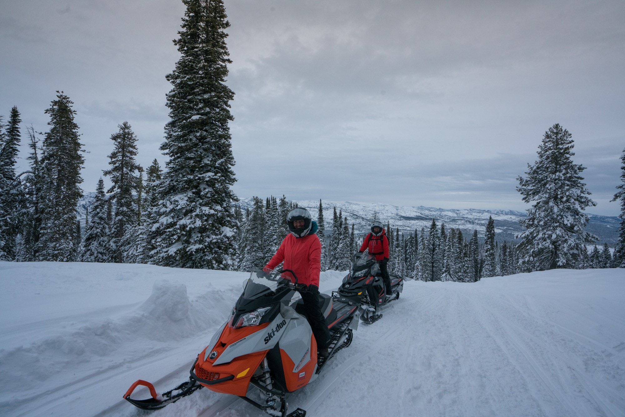 Two people on snowmobiles bundled up in warm clothes in winter landscape near McCall Idaho