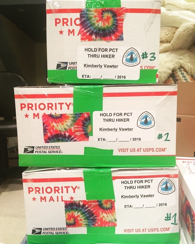 Three USPS priority mail boxes stacked on top of each other with tie-dye and green duct tape with "Hold for PCT thru-hiker Kimberly Vawter"