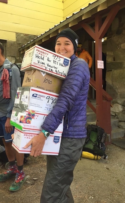 Woman holding 5 packages smiling outside a USPS