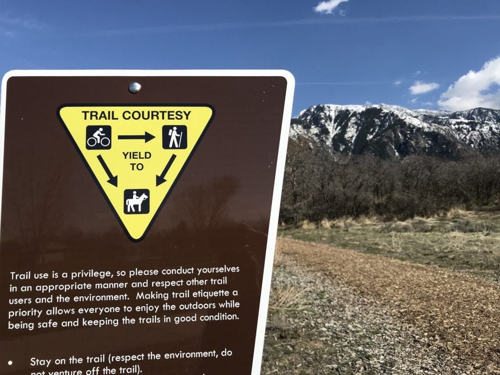 Trail courtesy sign showing that bikers yield to hikers and horses and that hikers yield to horses