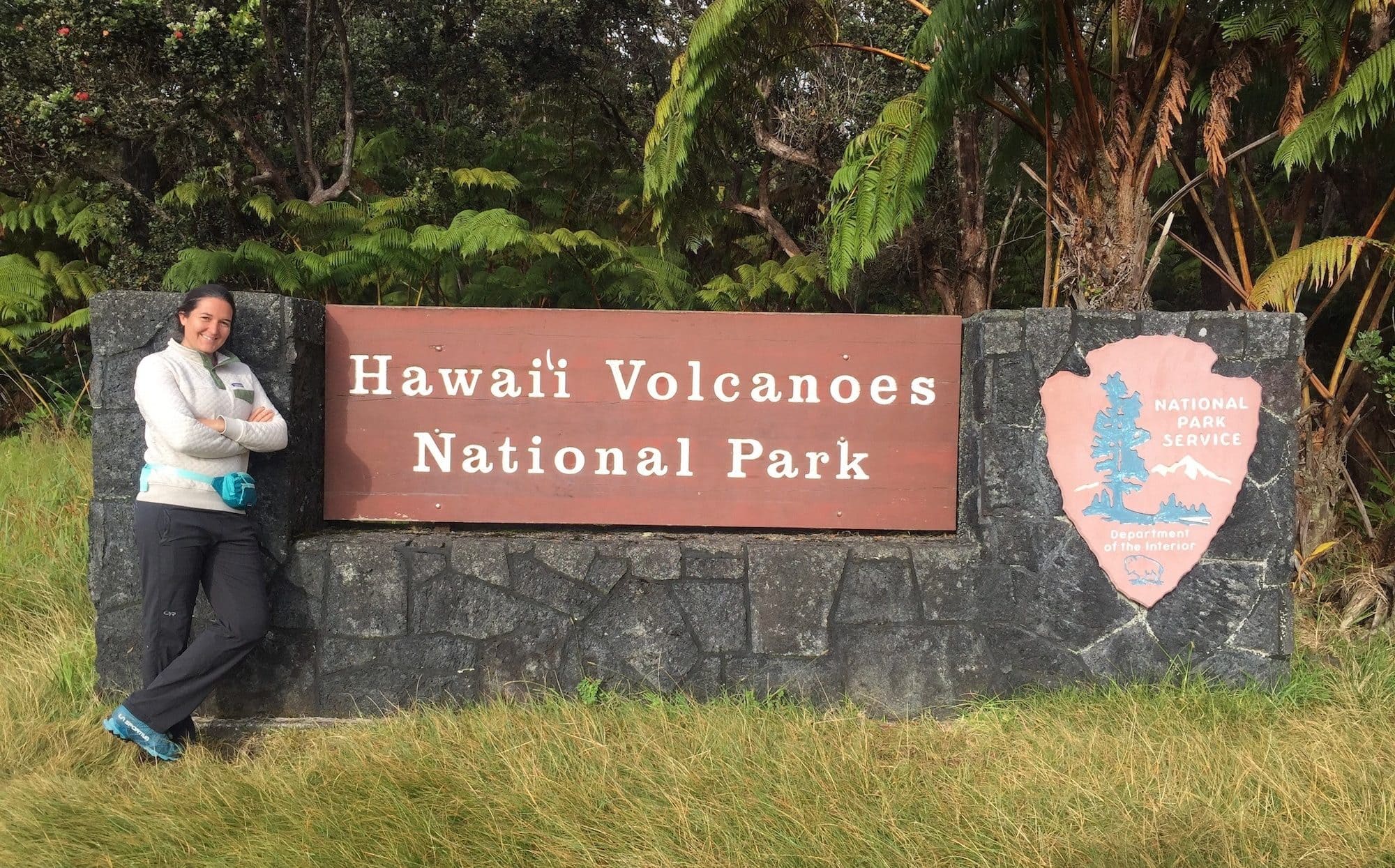 Kim standing next to Hawai'i Volcanoes National Park entrance sign