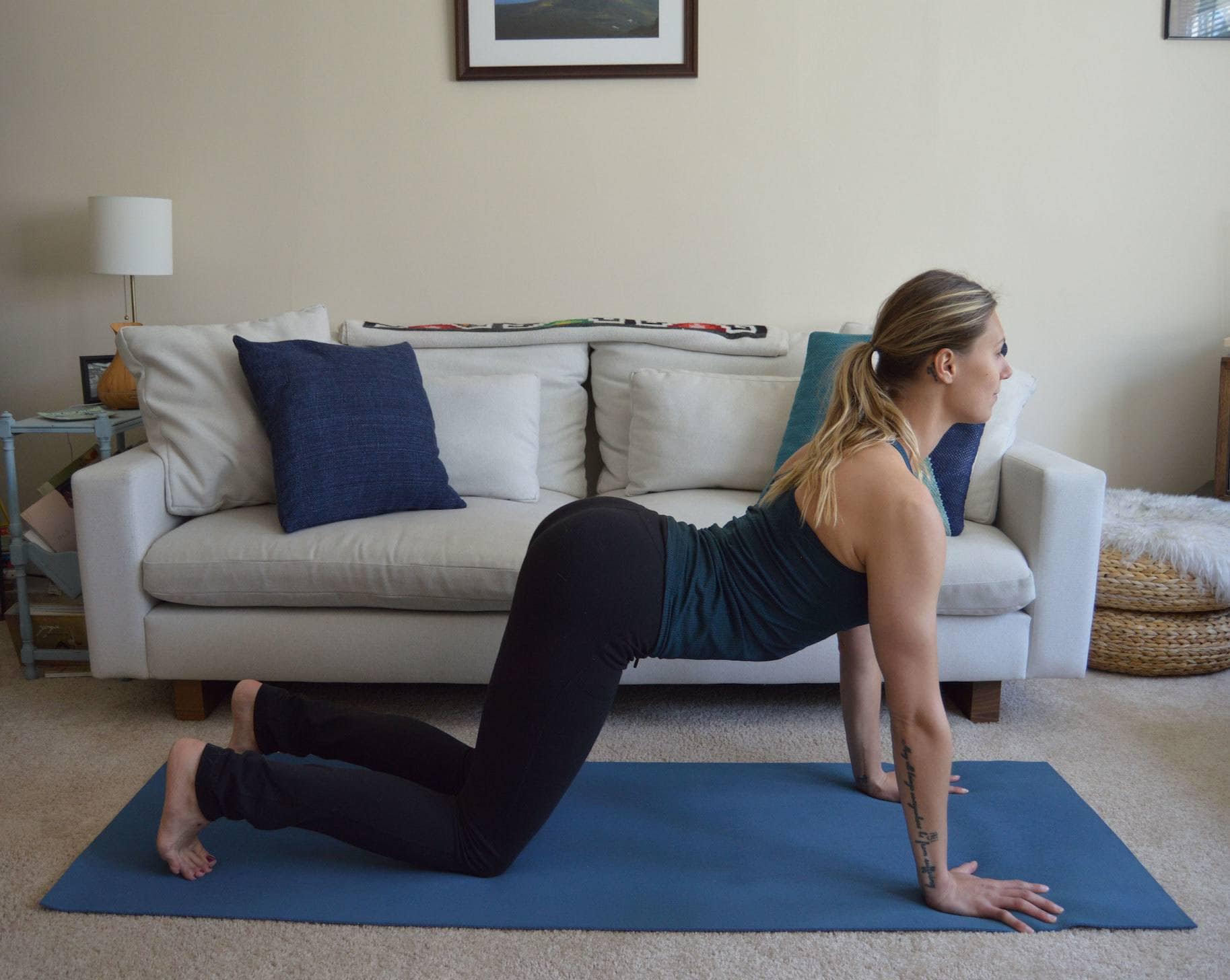 A woman does cow pose at home