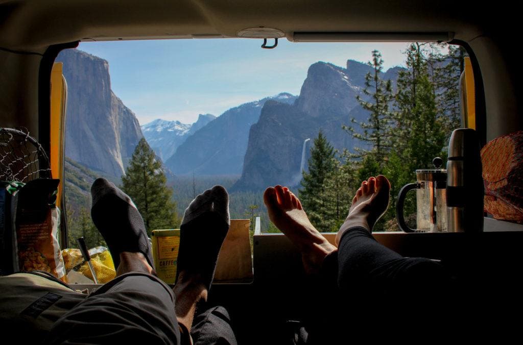 View of Yosemite Valley out the back of an Escape Campervan with a couple's feet in the foreground //  Enter to win a 4-day camper van rental with everything you need for an epic road trip.