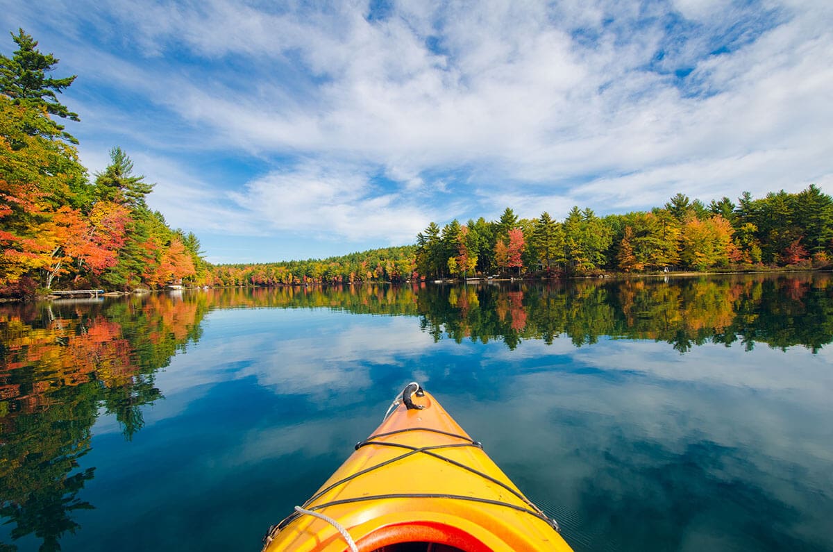 Bow of kayak on lake surrounded by fall foliage