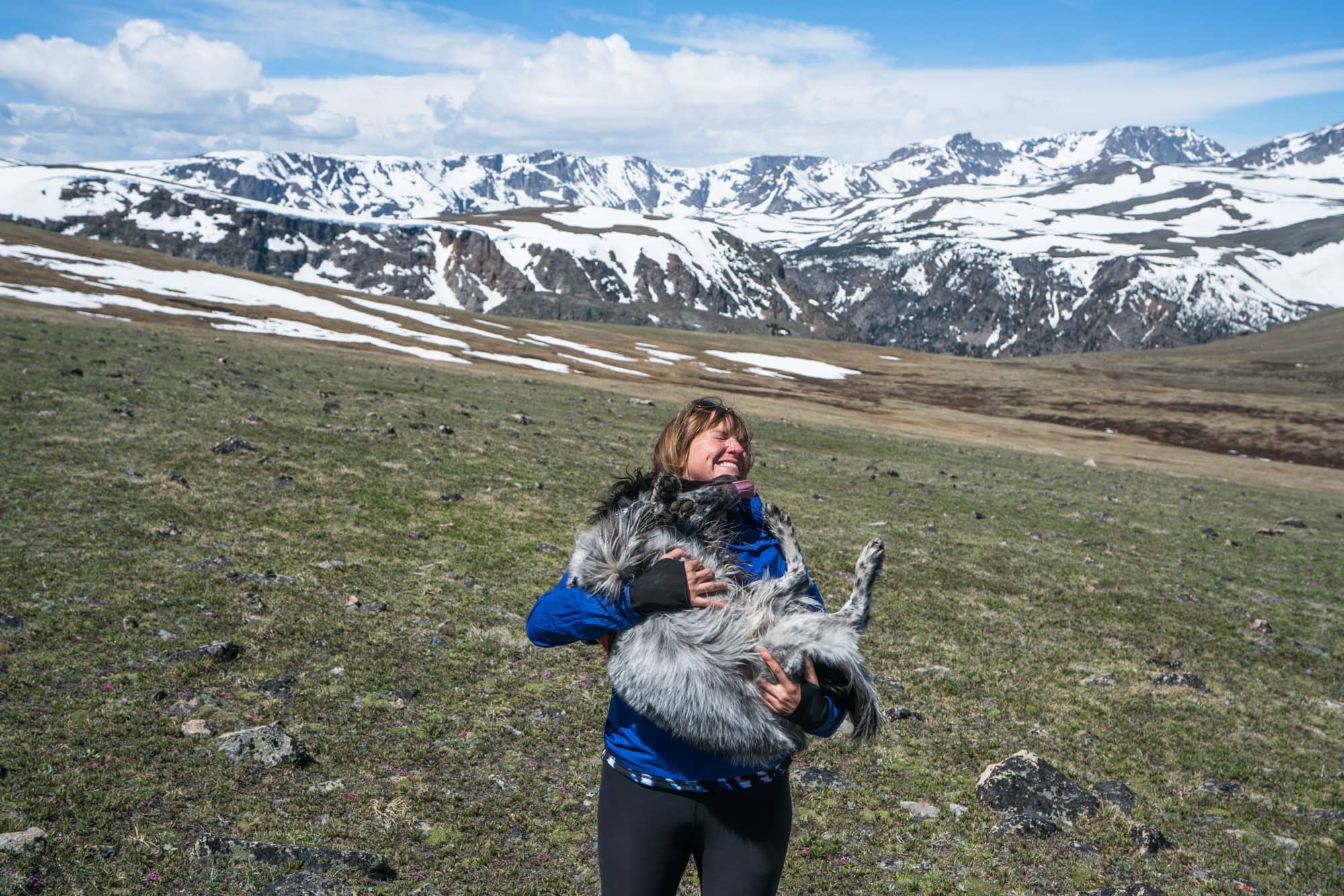 Kristen holding dog with snow-covered Beartooth Mountains in background