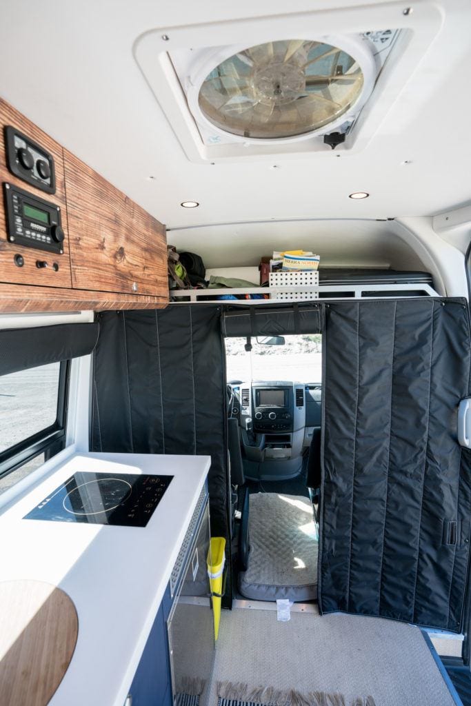 Black curtain separating back of converted camper van to cab